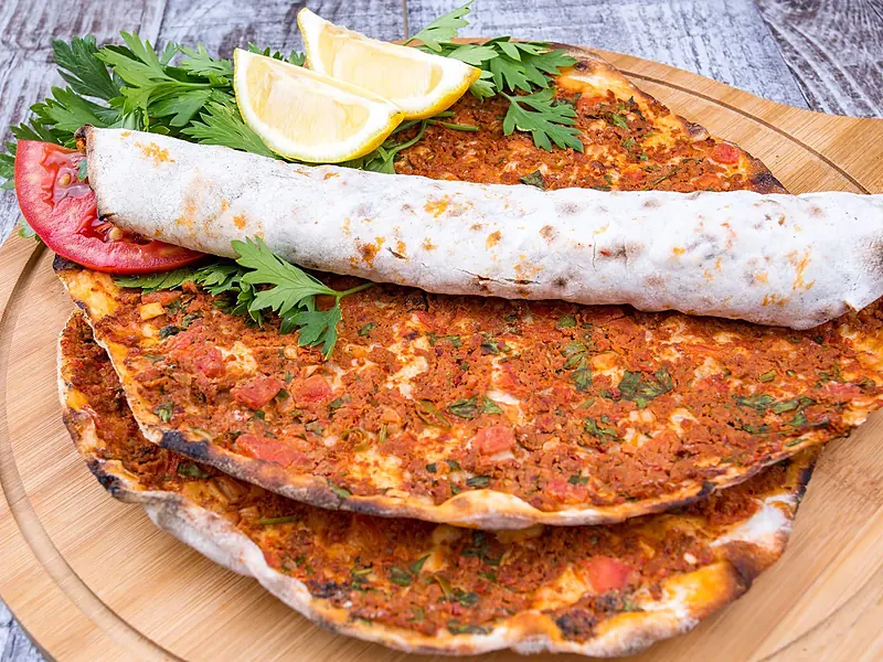 Lahmacun mit Petersilie und Zitrone auf einem Holzbrett