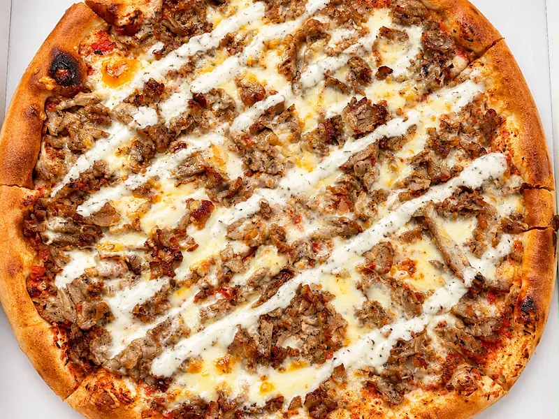 Pizza mit Kalbfleisch, Käse und Joghurtsoße im Karton