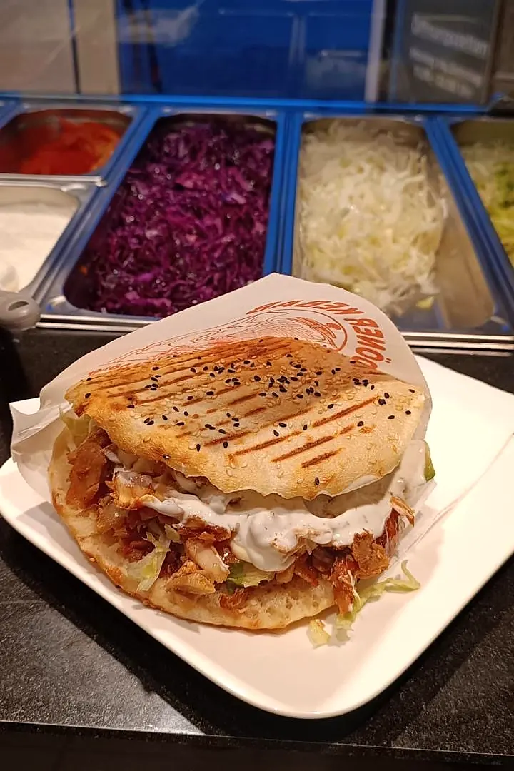 Döner im gegrillten Fladenbrot vor der Salattheke von Edeler Döner