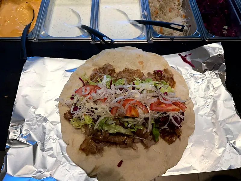 Yufka wird an der Theke mit Fleisch und Salat belegt